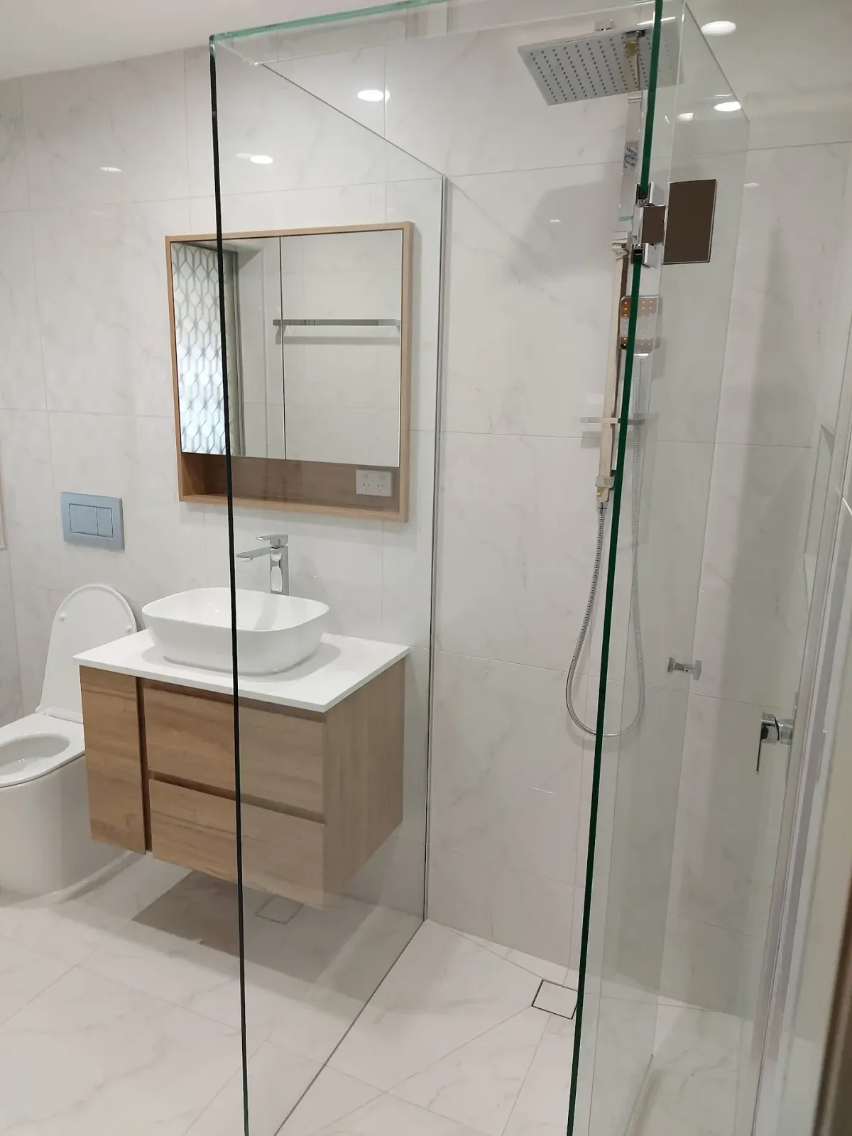 frameless glass shower, floating timber vanity and wall-hung toilet
