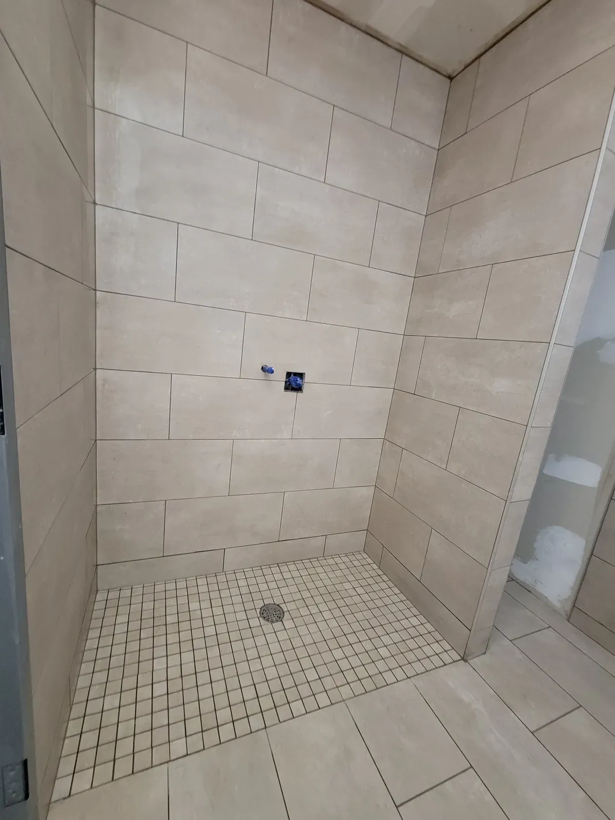 large-format tile shower with a mosaic floor, before trim and glass