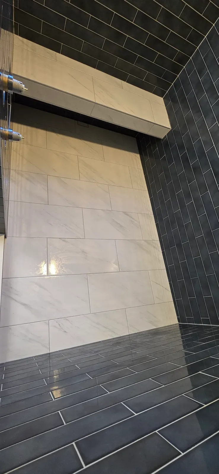 shower in navy and white large-format tile with a full-width ledge